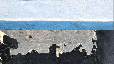 Абстрактна картина із жовто-сірою, сірою, білою, блакитною горизонтальними полосами на полущеній чорній бетонній стіні