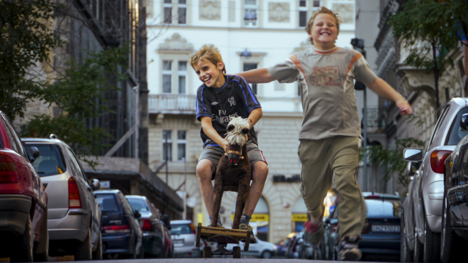 rus: Двоє усміхнених хлопчиків біжать по вулиці.