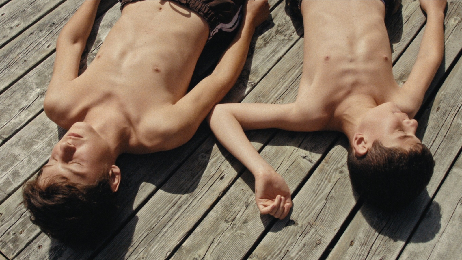 eng: Two brothers are sunbathing in the sun with their eyes closed.
