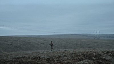 A military man stands in a field.