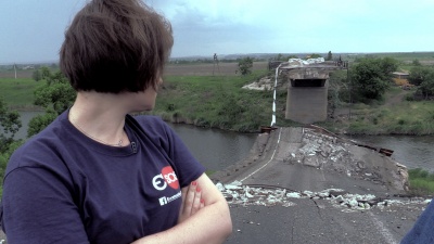 The young woman looks at the destroyed bridge.